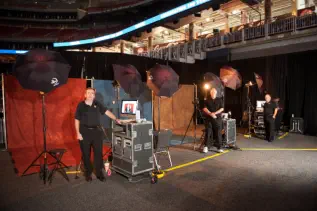 Three photographers standing in front of portrait stations at NRG Stadium